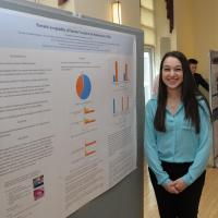 A student stands next to her poster presentation.